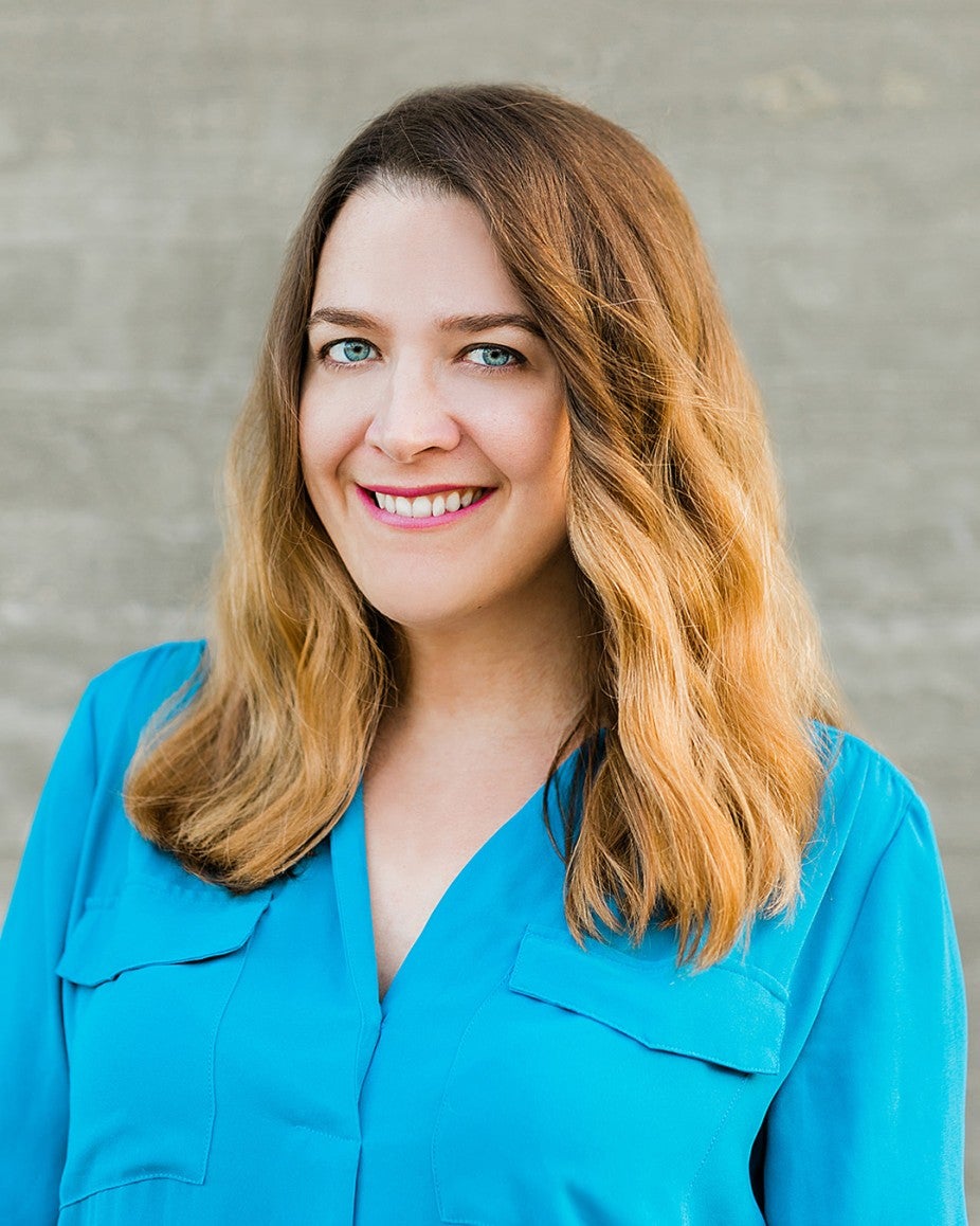 blonde woman smiling with bright blue shirt in daylight