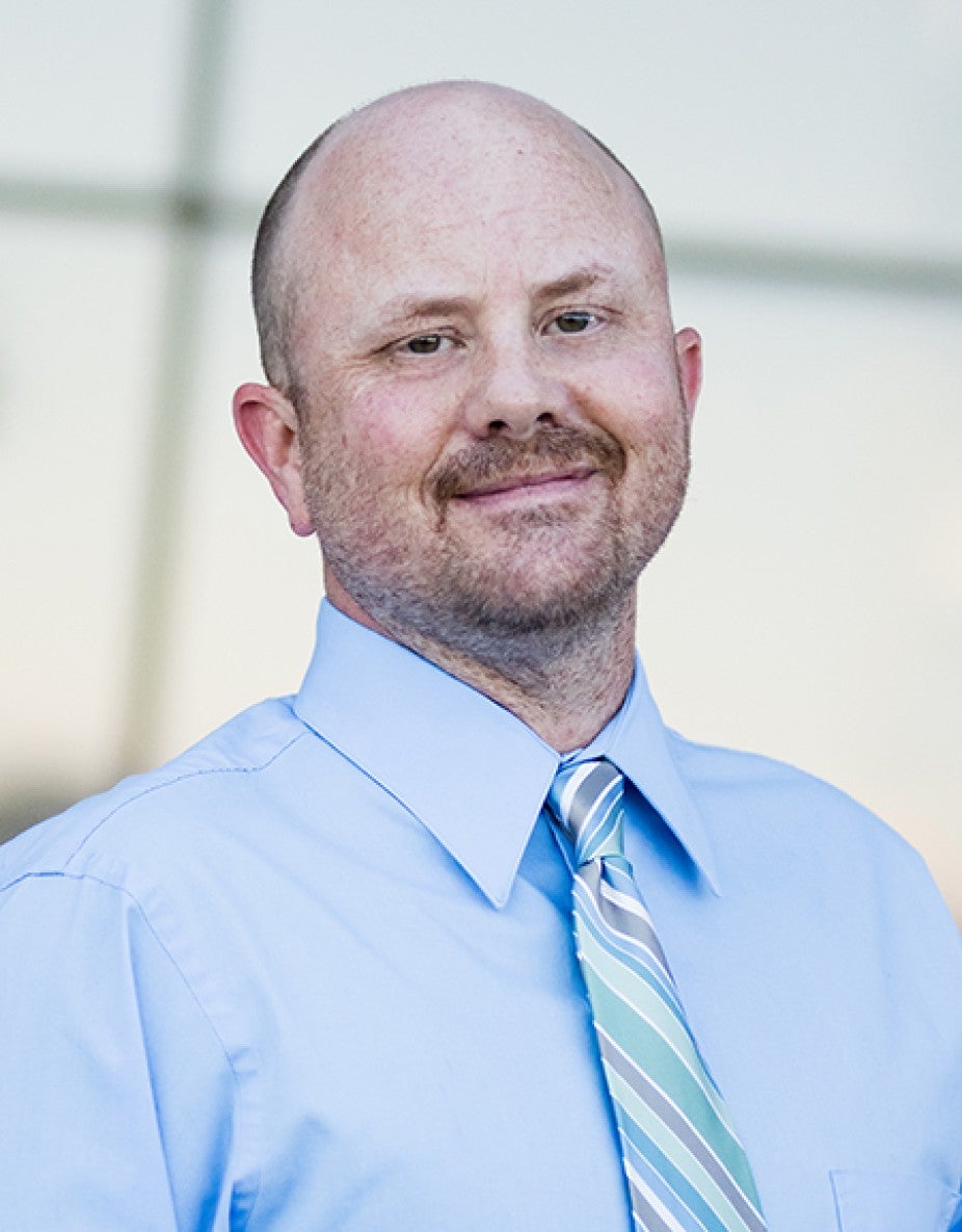 white man with blue shirt and green striped tie