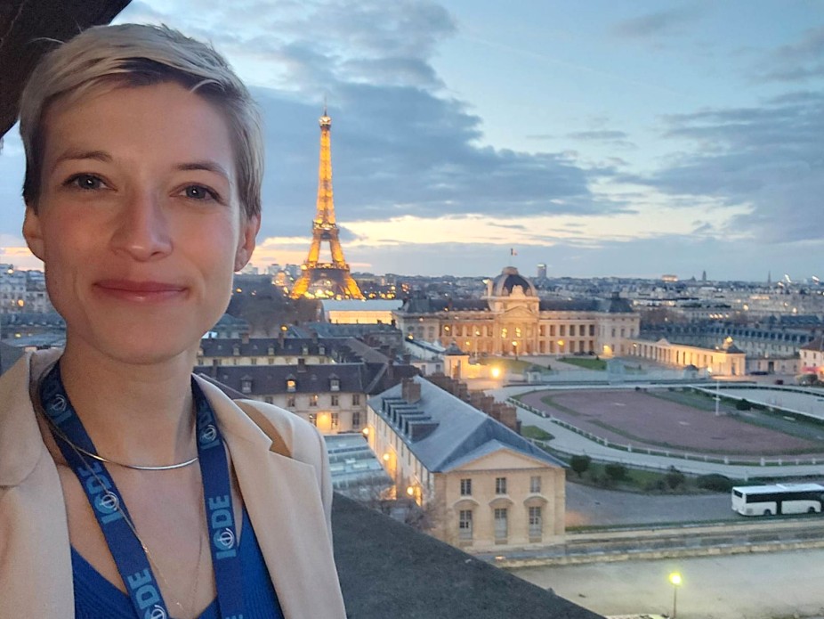 headshot of woman with short blonde hair with Eiffel Tower in the background