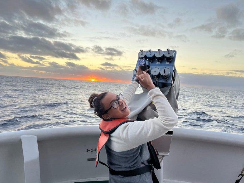 Woman wearing orange life vest on boat at sunset