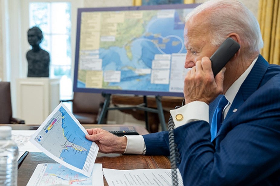 President Biden looking at a print out of maps