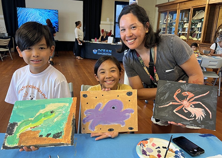 woman with children displaying their paintings