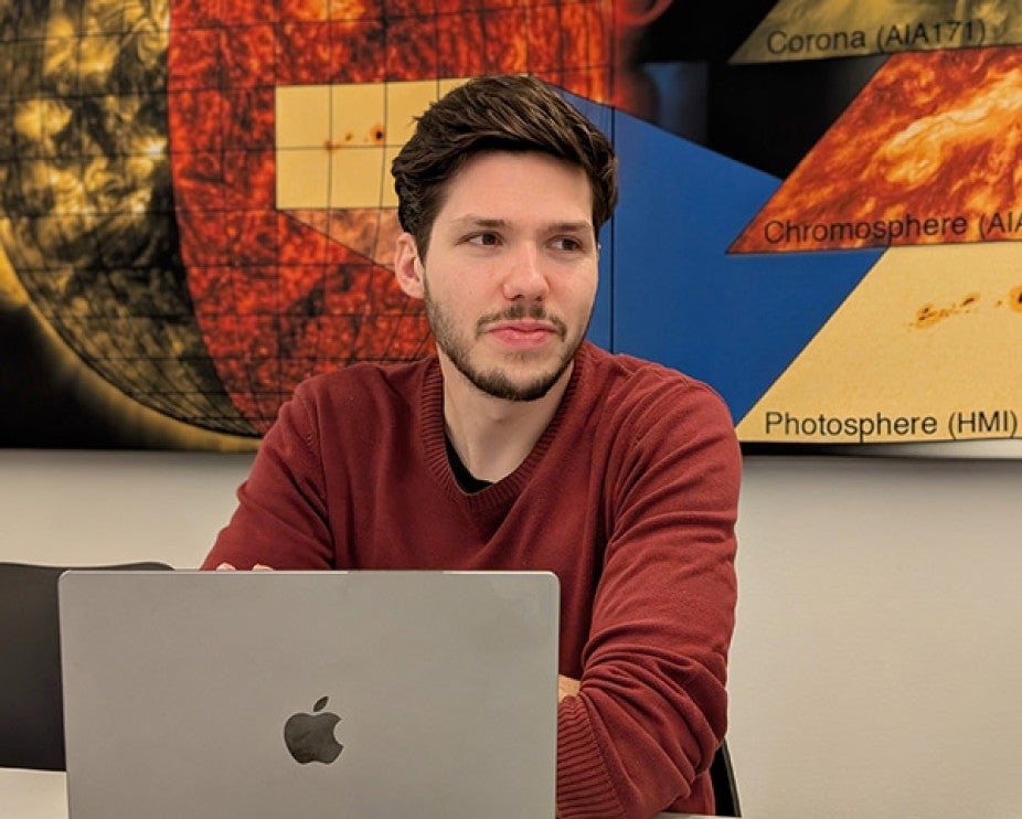 man in red sweater sitting in front of laptop