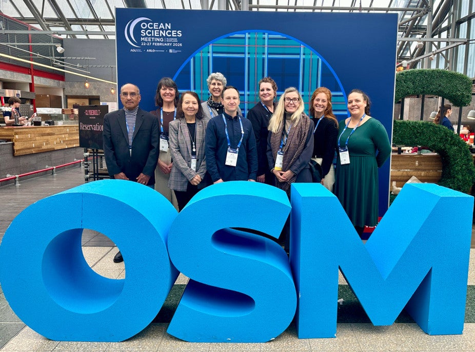 group photo behind giant blue OSM sign