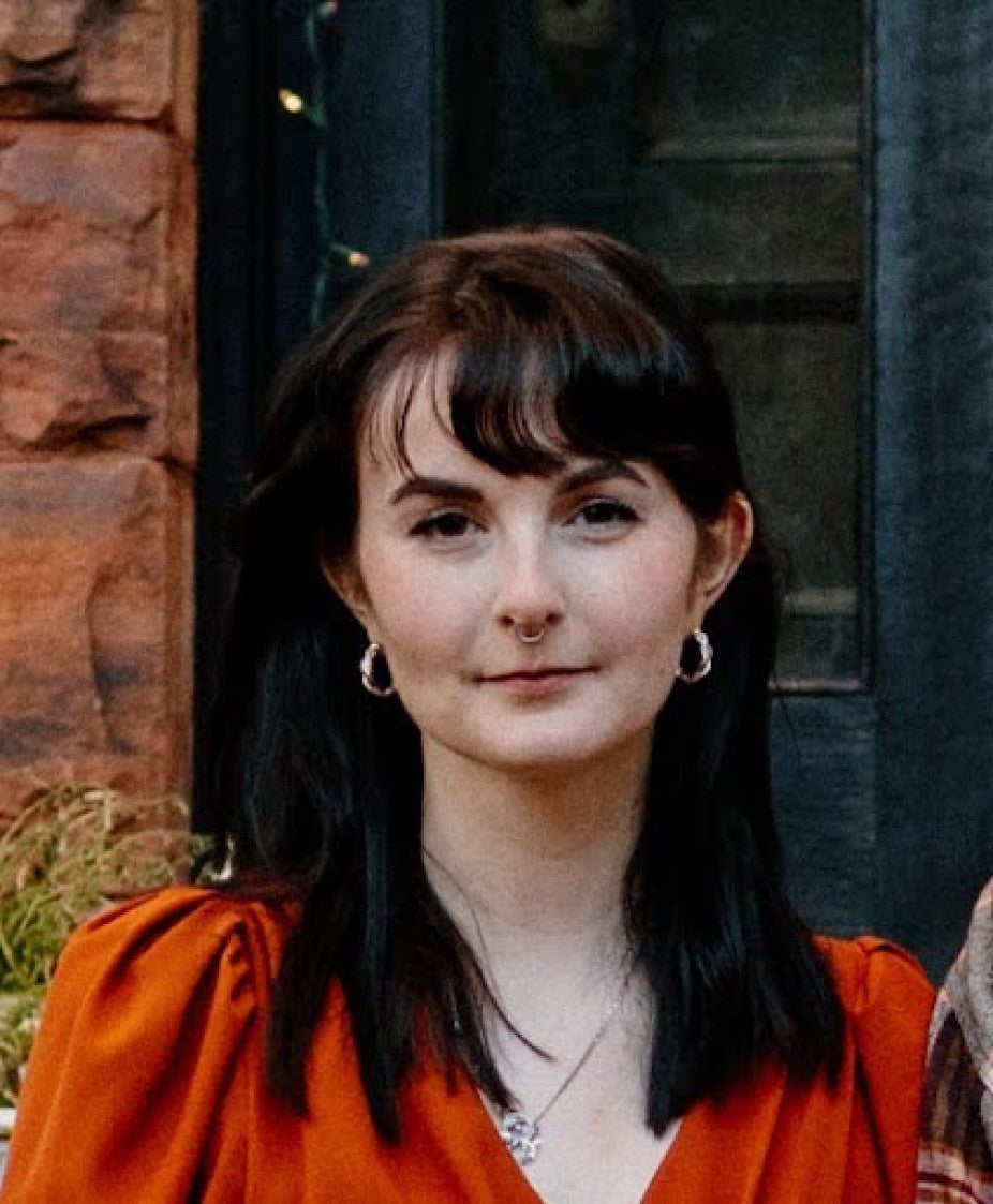headshot of woman with long dark hair wearing bright red shirt