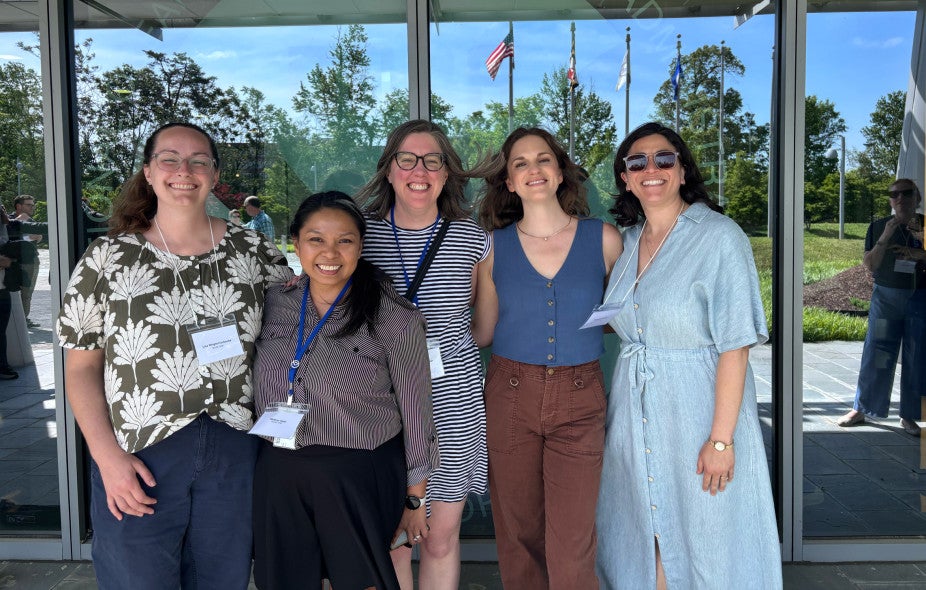 five women standing in front of a window