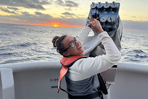 Woman wearing orange life vest on boat at sunset