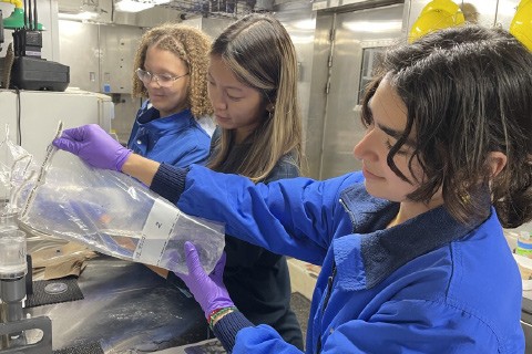 three women in blue jumpsuits filtering water samples