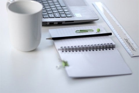 black pencil on notepad next to white coffee mug