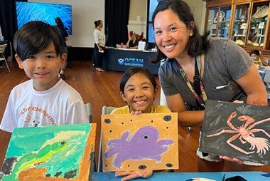 woman with children displaying their paintings